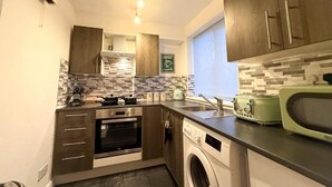 A compact kitchen with a dishwasher, oven, and a microwave. - 1 Bed - Sleeps 4 - WiFi & Free Parking (Redhill)