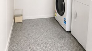 A laundry room with two stacked washing machines and a dryer, a small storage box, and a power outlet on the wall. - Entire home in Greenlane (Auckland)
