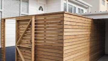 A wooden fence with a gate, a garage door, and a house with a red roof.