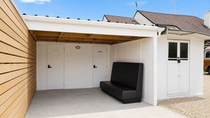 A covered outdoor seating area with a bench, a door, and a vehicle in the background. - Entire home in Greenlane (Auckland)