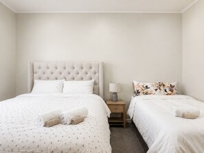 A hotel room with a large bed, a smaller bed, a nightstand with a lamp, and two rolled towels.