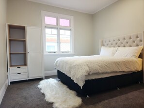 A bedroom with a bed, a wardrobe, a window, and a fluffy rug.