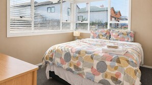 A bedroom with a bed, a bedside table, and a window with blinds. - Entire home in Greenlane (Auckland)