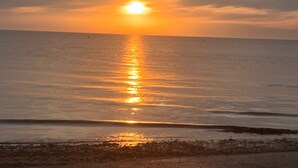 Ein Sonnenuntergang über einem ruhigen Meer mit einer felsigen Küste.