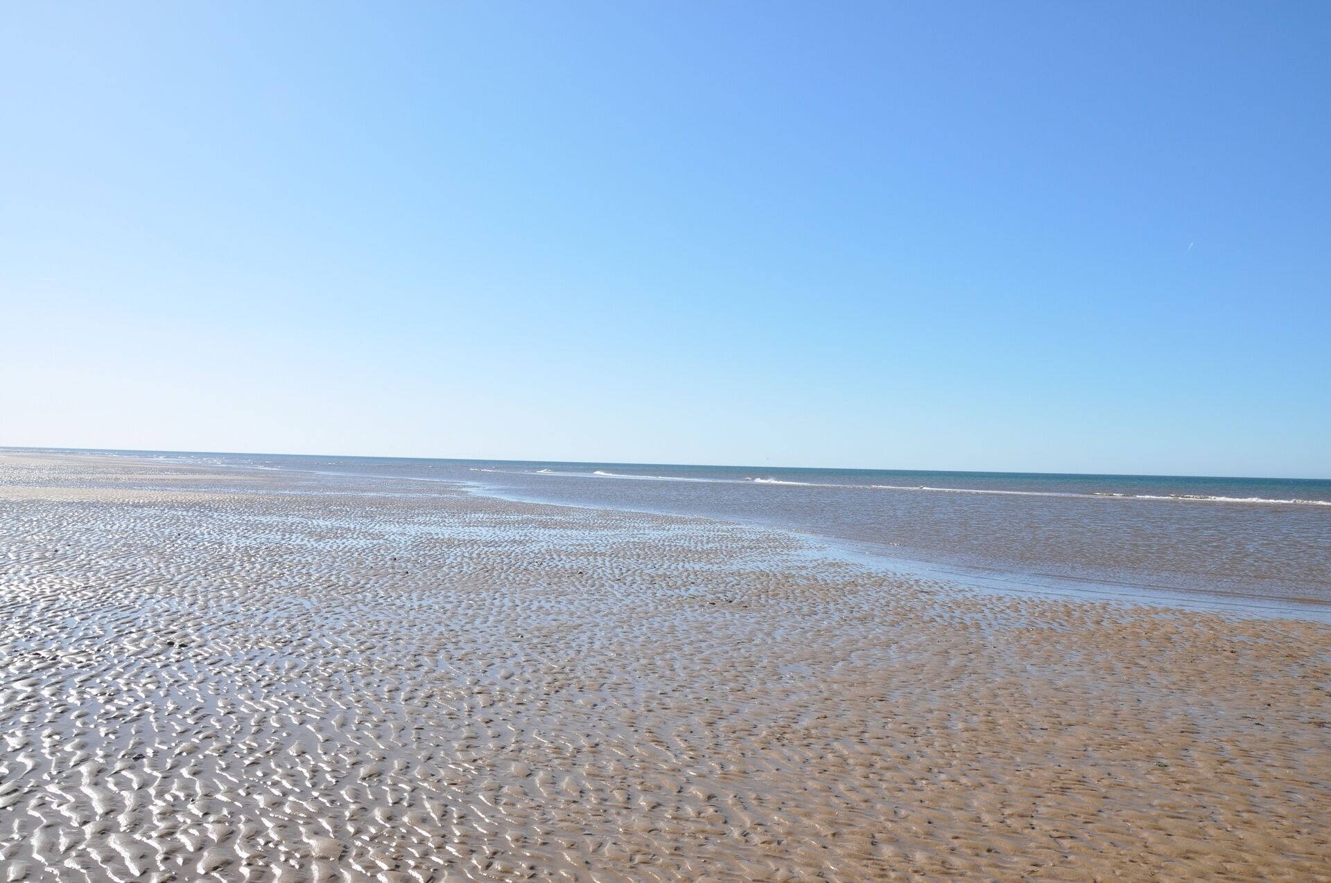 A beach with a wide expanse of sand and gentle waves.