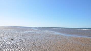 A beach with a wide expanse of sand and gentle waves.