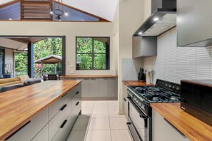 Une cuisine moderne dotée d’un îlot central, d’une cuisinière intégrée et de grandes fenêtres.