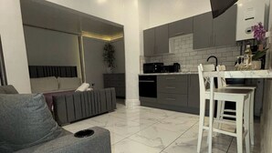 Une cuisine moderne avec un coin repas, un canapé gris et une chaise blanche.