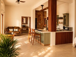 Un espacio habitable moderno con sofá, comedor, cocina y una pared de acento de piedra.