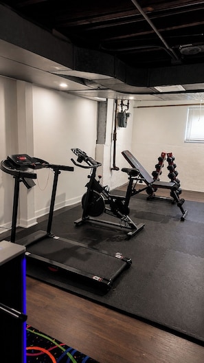 A gym with cardio equipment, weight benches, and a treadmill.