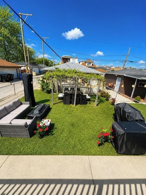 A backyard with artificial grass, a pergola, outdoor furniture, and a barbecue grill. - 4BR Retreat w/ Theater, Arcade, Gym and Firepit (Chicago)