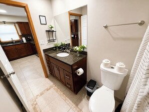 Een badkamer met toilet, wastafel, spiegel en een kleine prullenbak.