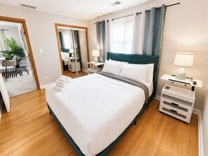 Een hotelkamer met een groot bed, nachtkastjes, een spiegel en uitzicht.