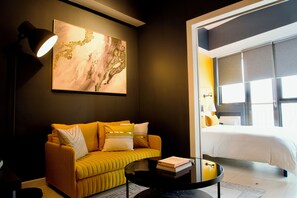 Ein modernes Hotelzimmer mit Sofa, Couchtisch, Bett und großem Fenster.