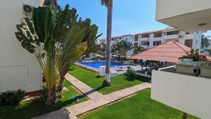 A pool area with a clear blue pool, surrounded by a well-maintained lawn and palm trees. - Apartment with pool near the beach in PV (Puerto Vallarta)