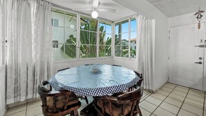 A dining area with a round table, chairs, a ceiling fan, and large windows with curtains. - Apartment with pool near the beach in PV (Puerto Vallarta)
