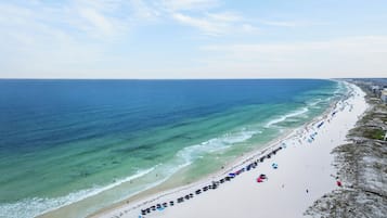 A beach with a long stretch of umbrellas and beachgoers.