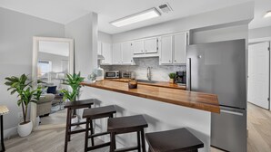 Een moderne keuken met witte kastjes, een houten aanrecht en een roestvrijstalen koelkast.