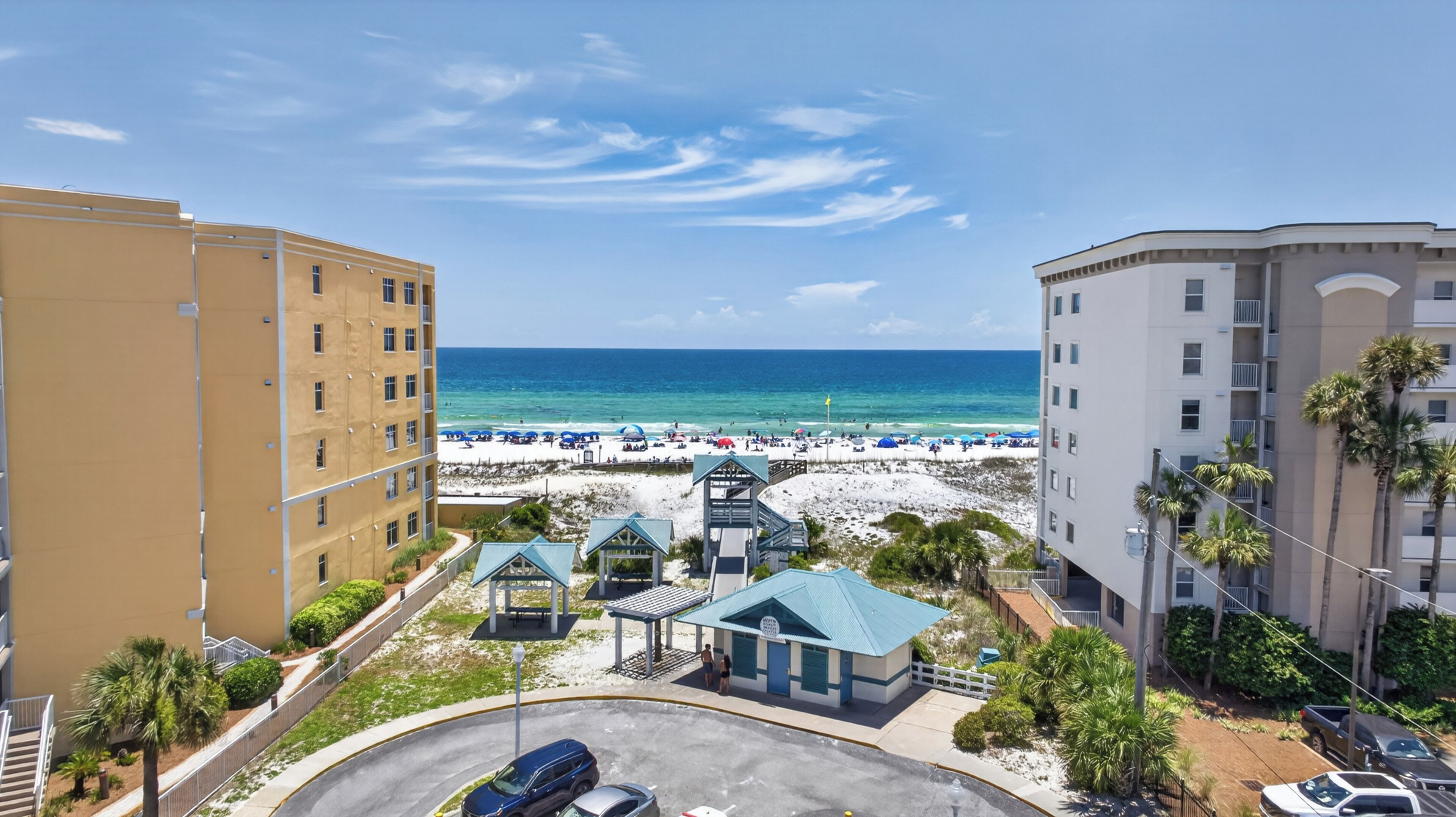 A beachfront hotel with a pool, beach umbrellas, and a view of the ocean.