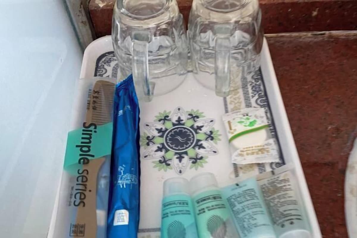 A tray with a decorative plate, two clear glasses, a blue bag, and several small items.