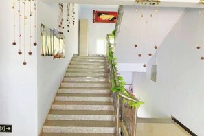 A staircase with a handrail, hanging decorations, and a red sign on the wall. - Guyuan hongbaoge Manor (Guyuan County)