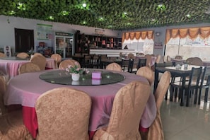 A restaurant with round tables, chairs, and a ceiling with greenery. - Guyuan hongbaoge Manor (Guyuan County)