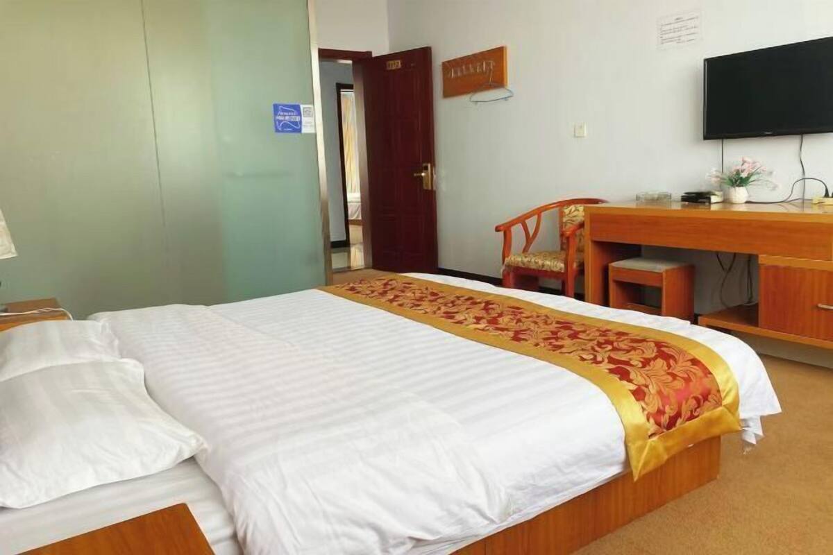 Hotellihuone, jossa on sänky, työpöytä, tuoli, televisio ja ovi.