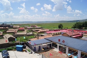 A rural area with multiple buildings, including a structure with a red roof and a blue building with a sign. - Guyuan hongbaoge Manor (Guyuan County)
