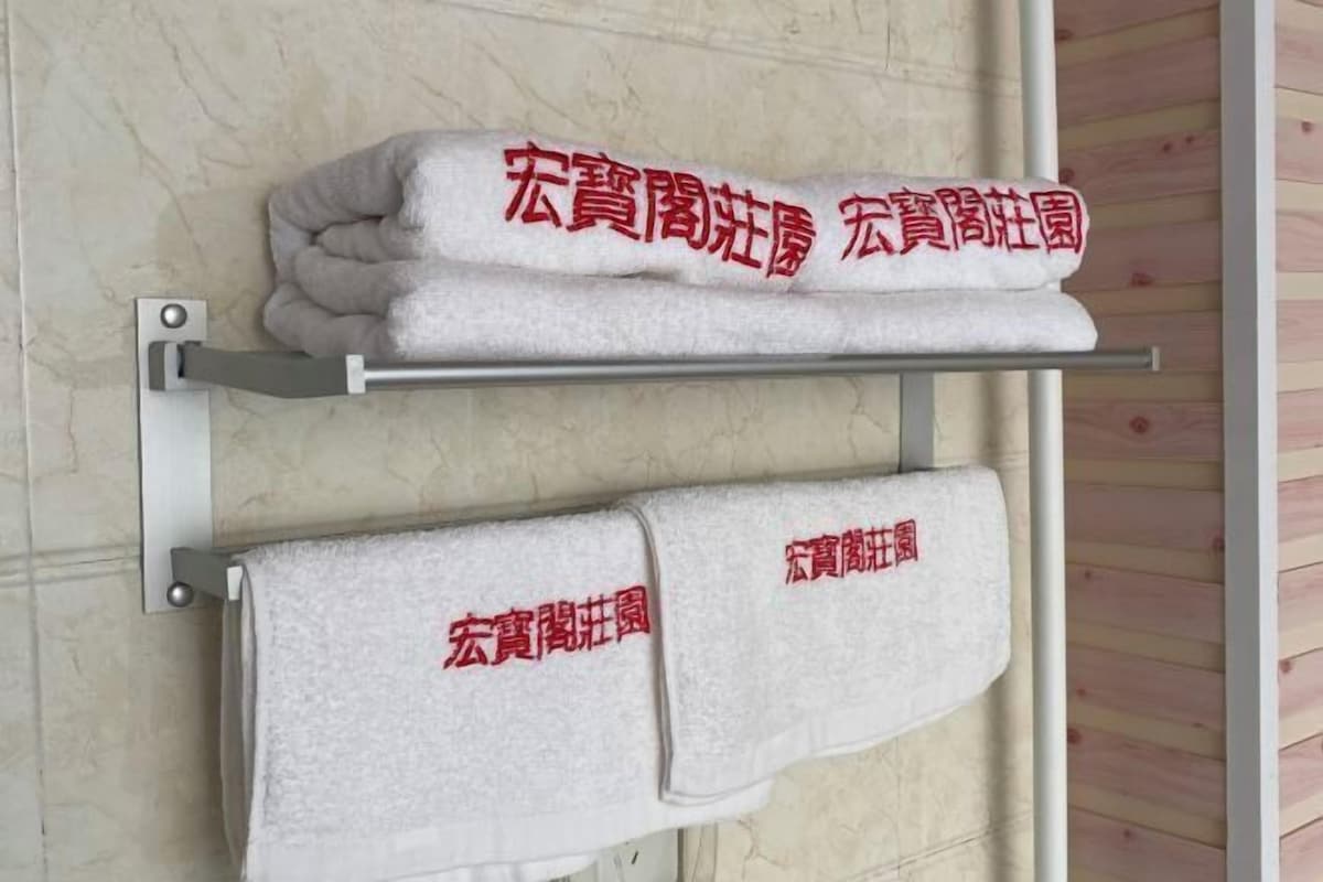 Two towels with red text on a metal towel rack against a wall.