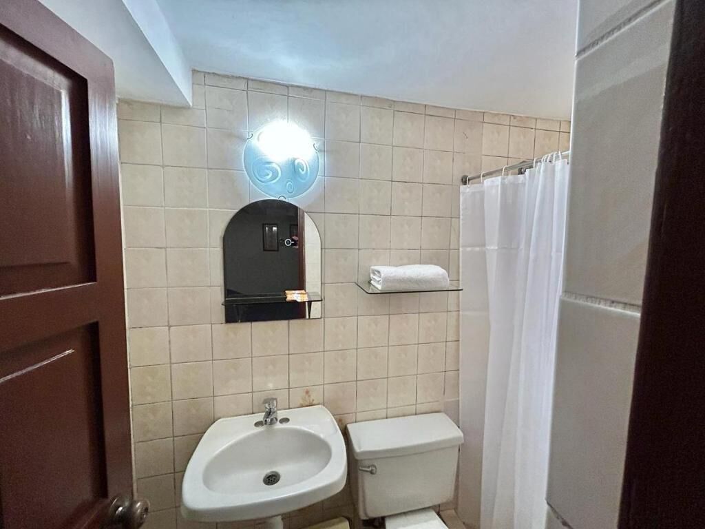 A bathroom with a sink, toilet, and a mirror with a light.