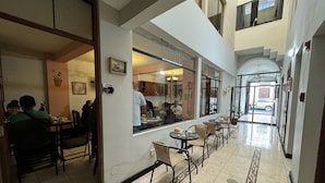 Un pasillo de hotel con un comedor, una escalera y vistas a la calle.