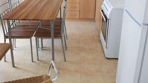 Una cocina con armarios de madera, un lavamanos de acero inoxidable, un refrigerador blanco y una mesa de comedor con sillas.