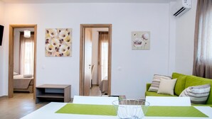 Una sala moderna con un sofá verde, una mesa de centro blanca y obras de arte en las paredes.