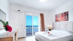 Habitación de hotel con cama, escritorio, silla, un cuadro y vista al mar.