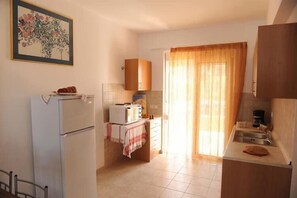 A compact kitchen with a refrigerator, a microwave, and a sink. - Gennadi Gardens Apartments (Rhodes)