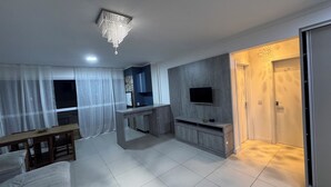 Una sala de estar moderna con televisión, un comedor y una cocina independiente.