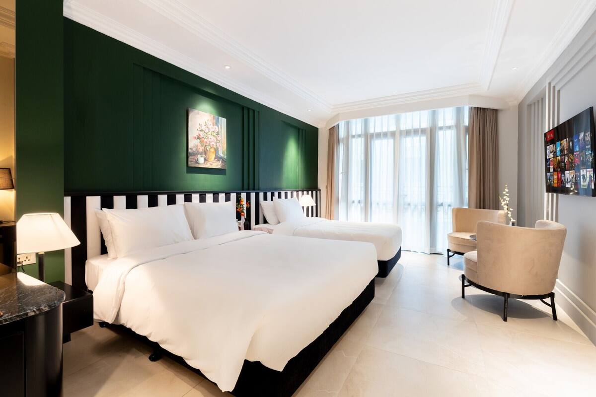 Een hotelkamer met twee bedden, een televisie, een stoel en een groot raam.