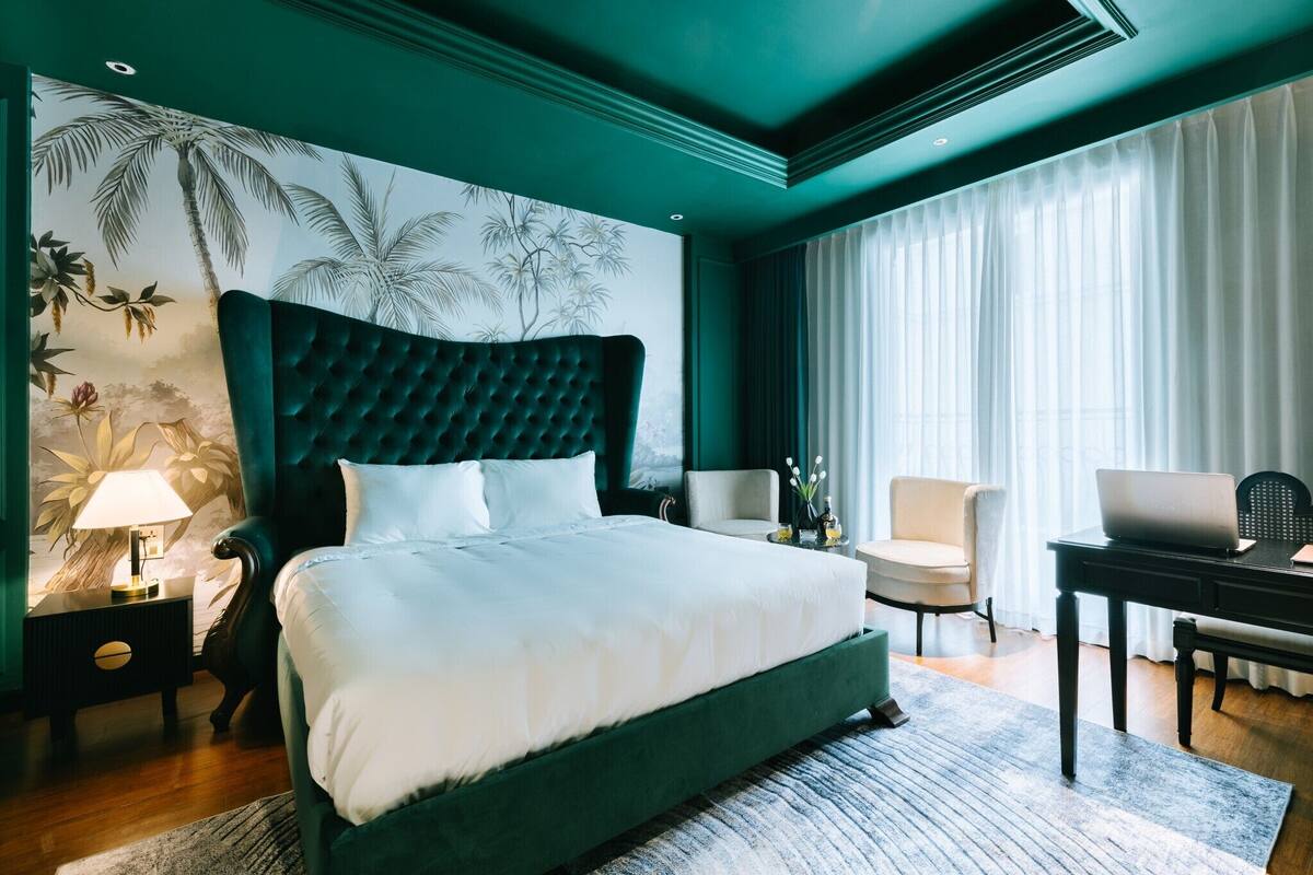 Een slaapkamer met een groot bed, een bureau, een stoel en een nachtkastje.