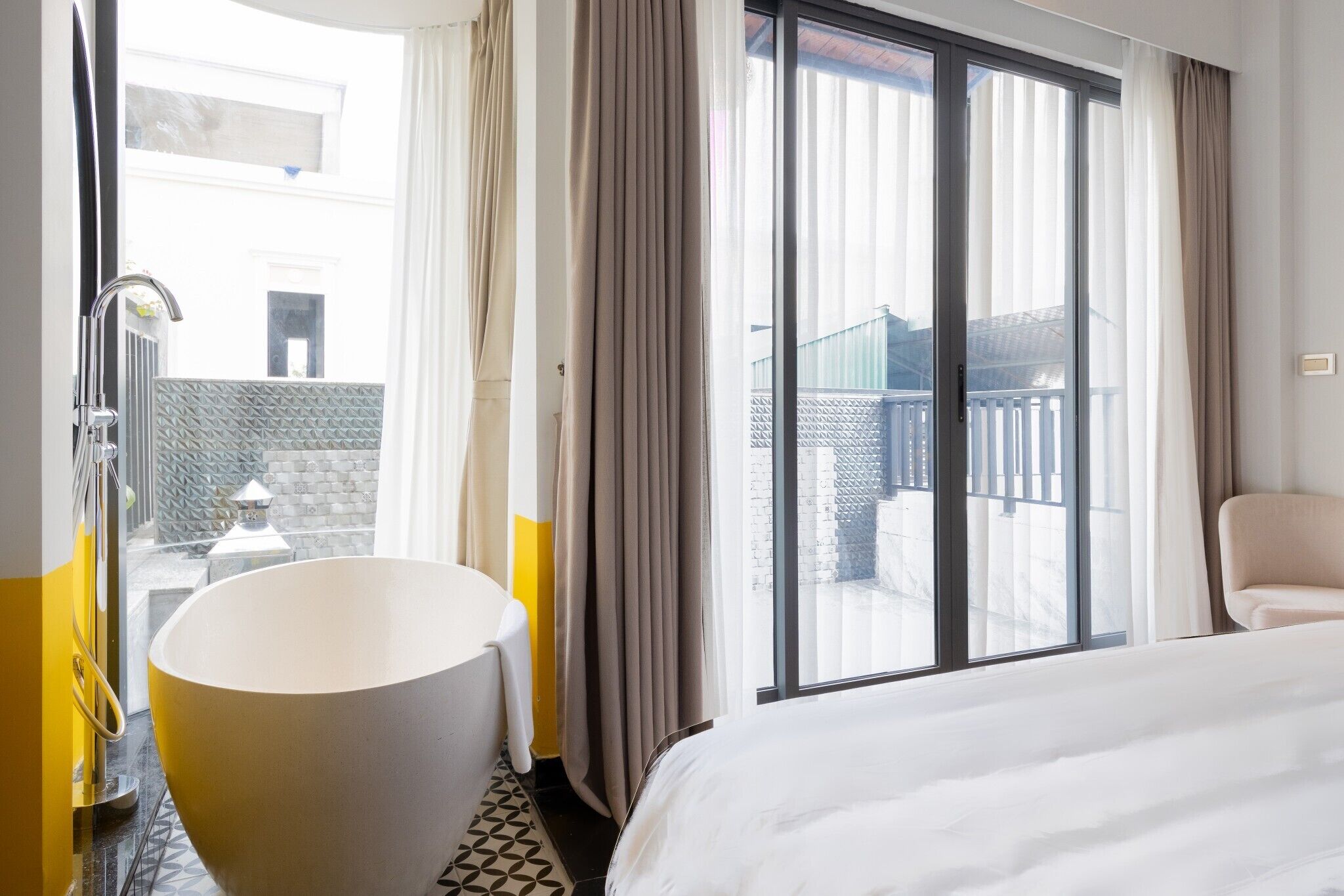Una habitación de hotel con una bañera grande, una cama y un balcón con vistas.