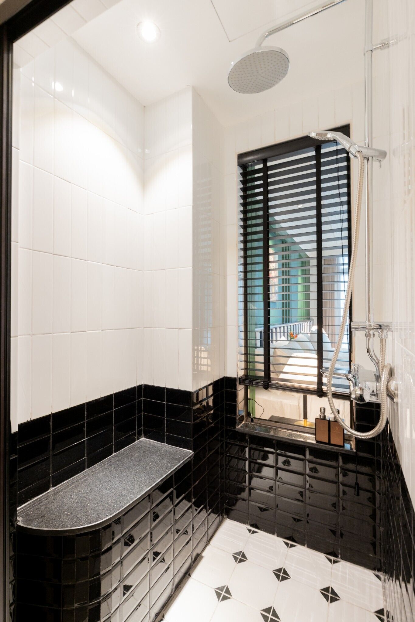 A modern bathroom with a shower, a bench, and a view through a window.