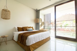 A modern bedroom with a large bed, a hanging light fixture, and a view of the outside. - Pelangi 148 (Seminyak)