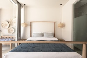 A modern bedroom with a wooden bed frame, a large window with curtains, and woven wall decorations. - Pelangi 148 (Seminyak)