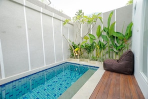 A small pool with blue tiles, surrounded by plants and a wooden deck. - Pelangi 148 (Seminyak)