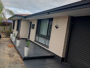 A modern house with a brick exterior, large windows, and a black garage door. - Budget Friendly Accommodation near the Train  Station 
Cosy Private Rooms (Mandurah)