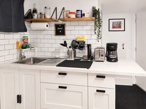 A modern kitchen with white cabinets, a stainless steel sink, a coffee maker, and a toaster. - 1 Bedroom Apartment Near MetLife Stadium & EWR Airport (Newark)