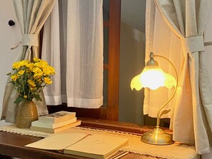 Un escritorio con una lámpara, un florero con flores y libros.