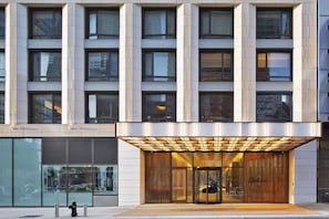Ein modernes Gebäude mit einer markanten Eingangspartei, deren Fassade aus Holz besteht und die eine Glastür aufweist.