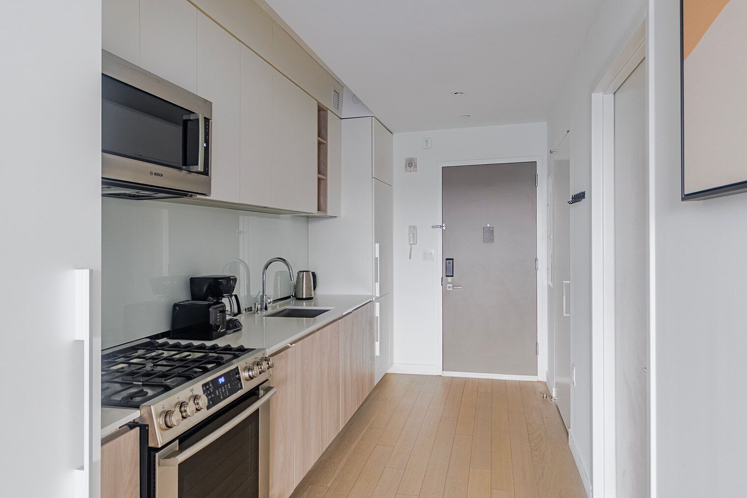 A modern kitchen with a gas stove, microwave, and coffee maker.