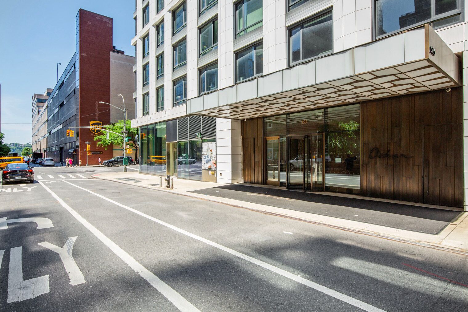 Een modern gebouw met een glazen gevel, een UPS-winkel en een straat met aangegeven rijstroken.