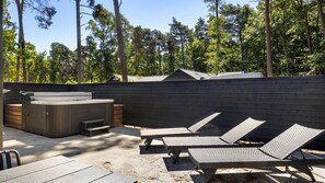 Eine Terrasse im Freien mit Whirlpool, Liegestühlen und einer Holzverkleidung.